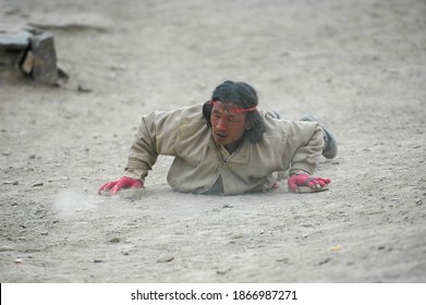 Gansu, China. Feb 27, 2007. A Tibetan Buddhist pilgrim does full body prostrations. He kneeling down, sliding the forearms along the road, prostrating himself on the ground.