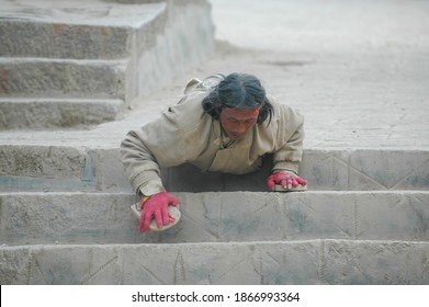 Gansu, China. Feb 27, 2007. A Tibetan Buddhist pilgrim does full body prostrations. He kneeling down, sliding the forearms along the steps, climbing downstairs.