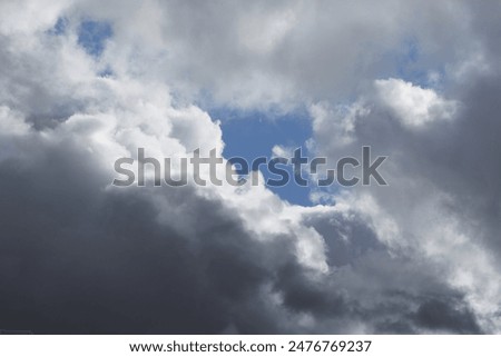 A gap in dense clouds through which the blue sky is visible