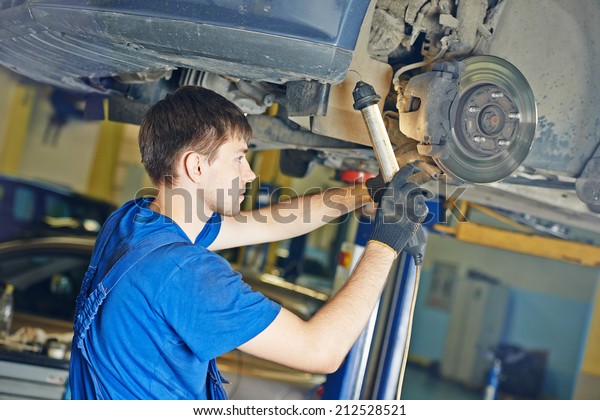 garage auto\
mechanic repairman checking car brake during automobile maintenance\
at repair service\
station