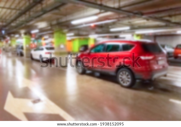 Garage car blurred. Car lot parking space in\
underground city garage. Empty road asphalt background in soft\
focus. Concrete skeleton for parking\
car