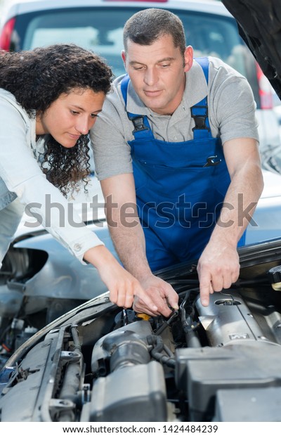 garage client\
pointing at car battery to\
mechanic