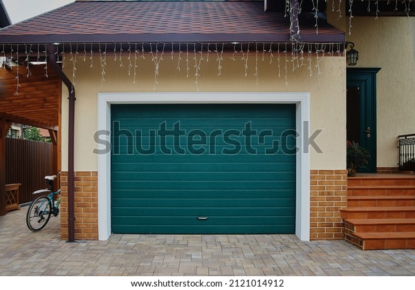 Garage Door. A garage with blue doors at the\
end of a driveway.
