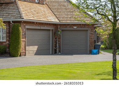 Garage door in luxury house with trees and nice landscape in Spring in Vancouver, Canada, North America. Day time on April 2025.