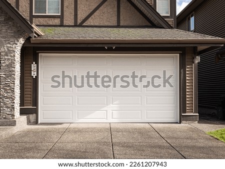 Garage Door. Modern house with garage door that is closed. A perfect neighbourhood. Family house with wide garage door and concrete driveway in front. Street photo, nobody