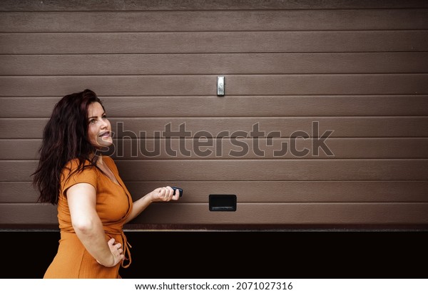  Garage door PVC. Girl or\
young woman holds remote controller for closing and opening garage\
door