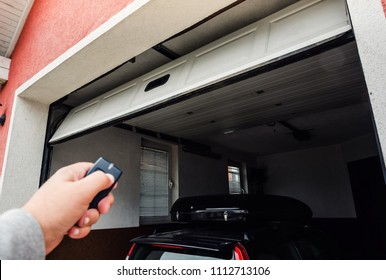 Garage door PVC. Hand use remote controller for closing and opening garage door.
 - Shutterstock ID 1112713106
