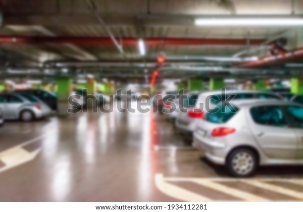 Garage interior blurred. Car lot parking space in\
underground city garage. Empty road asphalt background in soft\
focus. Large private\
garage
