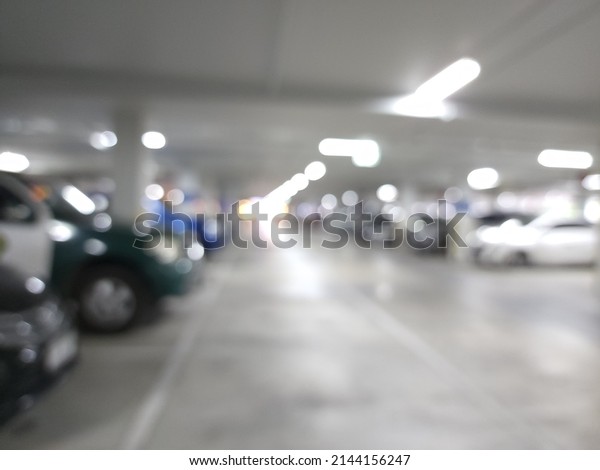 Garage interior blurred. Car lot parking space in\
underground city garage. Empty road asphalt background in soft\
focus. Large private\
garage