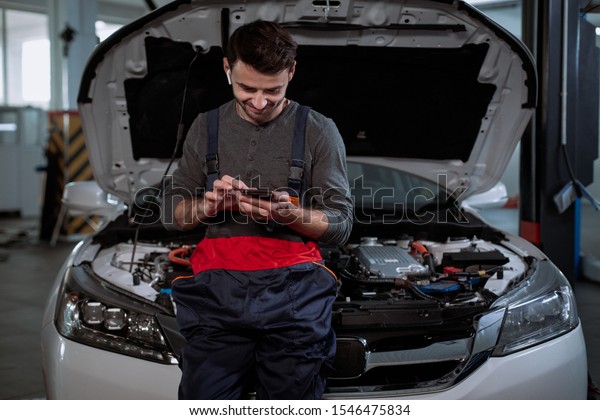 In the garage mechanic guy very attractive
listening music from his wireless headphones and take a look on his
phone while have the break
time