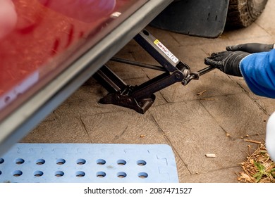 Garage Mechanic. Using Scissor Jack Lift To Lift A Car To Repair Change Wheel. DIY Car Vehicle Repair Maintenance