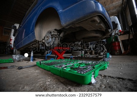 The garage is a small business auto repair shop. Multi-functional auto mechanic's tool set. A car in need of rear axle suspension repair was raised on a hydraulic lift. Foto stock © 