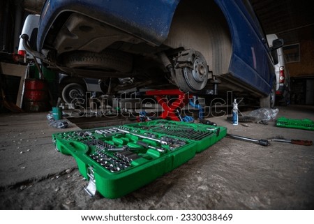 The garage is a small business auto repair shop. Multi-functional auto mechanic's tool set. A car in need of rear axle suspension repair was raised on a hydraulic lift. Foto stock © 