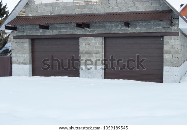 Garage stone with roller shutters in brown color for\
two cars