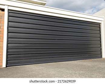 Garage With Tilt-up Retractable Metal Door Painted Black. Copy Space Stock Photo.