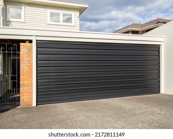 Garage With Tilt-up Retractable Metal Door Painted Black. Copy Space Stock Photo.