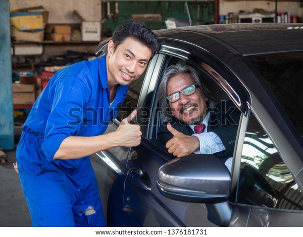 garage worker\
concept.Smiling happy asia mechanic technician worker at car \
repair service station and thumb up\

