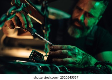 In a garage workshop, a mechanic is seen using a screwdriver to fix a car engine, highlighting his dedication to precision and mechanical skill in a detailed environment. - Powered by Shutterstock