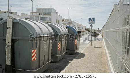 Garbage bins sharp in foreground with shallow defocused background on a sunlit sidewalk street; background backdrop copyspace calm.