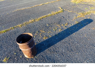 Garbage Can In A Metal Barrel Outside On Asphalt At The Parking Lot.