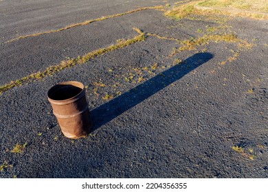 Garbage Can In A Metal Barrel Outside On Asphalt At The Parking Lot.