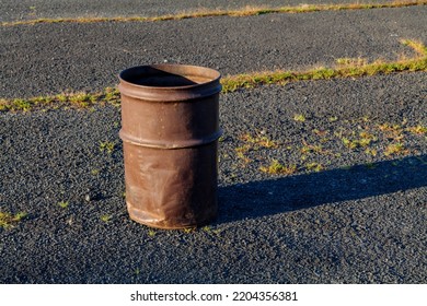 Garbage Can In A Metal Barrel Outside On Asphalt At The Parking Lot.