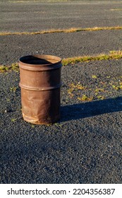 Garbage Can In A Metal Barrel Outside On Asphalt At The Parking Lot.