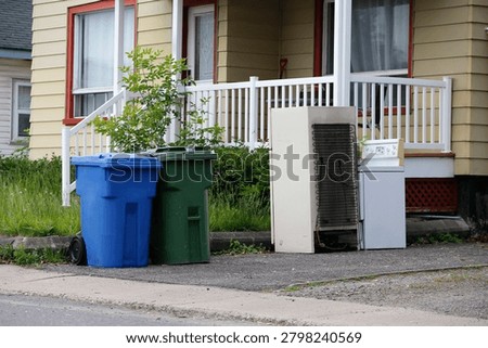 Garbage cans in front of a house in Quebec City. An old refrigerator and an old stove in the trash.