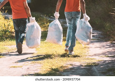 Garbage Collection. People Carry A White Construction Bag Full Of Rubbish