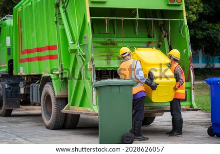 Garbage collection service,Rubbish cleaner man in a uniform working together on emptying dustbins for trash removal with truck loading waste and trash bin,Recycling concept.