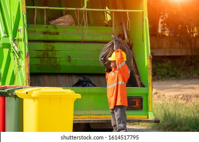 Garbage collection worker putting bin into waste truck for removal with truck loading waste.