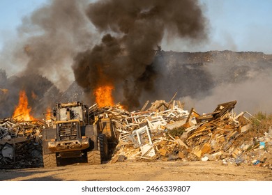 Garbage dump bulldozer pushing trash during a landfill fire - Powered by Shutterstock