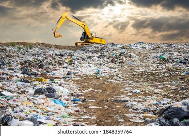 garbage dump pile in trash dump or landfill,backhoe and truck is dumping the gabage from municipal,garbage dump pile and dark sky background  ,pollution concept