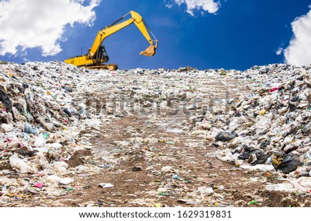 garbage dump pile in trash dump or landfill,backhoe is dumping the gabage from municipal,garbage dump whit old backhoe and blue sky