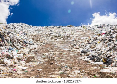 Garbage Dump Pile In Trash Dump Or Landfill,truck Is Dumping The Gabage From Municipal,garbage Dump Pile And Blue Sky Background With Flare From Sun ,pollution Concept