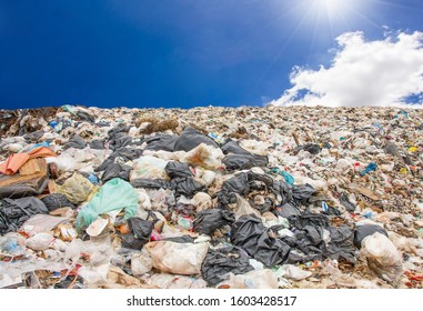 Garbage Dump Pile In Trash Dump Or Landfill,truck Is Dumping The Gabage From Municipal,garbage Dump Pile And Blue Sky Background With Flare From Sun ,pollution Concept