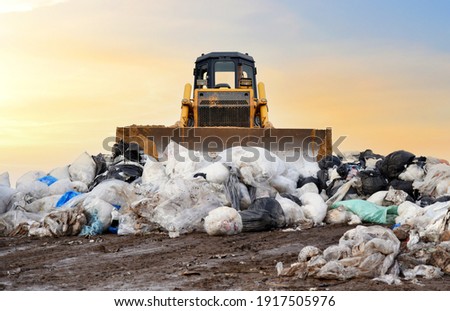 Garbage dump with plastic bags and food waste. Recycling of construction waste on junk yard. Refuse collection. Bulldozer dispose of rubbish at a landfill. Trash disposal area. Dozer on rubbish dump 