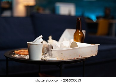 Garbage In Empty Living Room With Food Trash, Bottle Of Booze And Napkins On Blue Sofa. Misery House Apartment Of Lonely Woman With Mental Depresion Having Misery, Rubbish With No People In