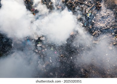 Garbage and fire burn in landfill. Also call trash, waste, rubbish. Destruction with combustion, heat, flame. Occurs smoke, toxic cause of air pollution, environmental damage and global warming.