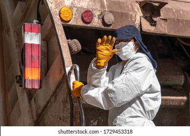 Garbage man in respiratory mask collects rubbish to garbage car in Cusco, Peru during coronavirus pandemic in Latin South America. Epidemic of coronavirus covid-19