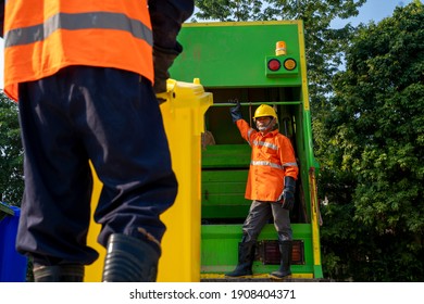 Garbage man working together on emptying dustbins for trash removal.