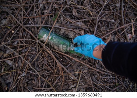 garbage in the nature, cleaning the environment in the spring on the river from the rubbish a woman in disposable latex blue mittens in to blue large plastic bag