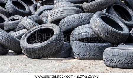 Garbage from a pile of black old car tires. Environmental pollution. Ecological problems. Old car tires thrown into an industrial landfill for recycling. Reuse of worn rubber tires