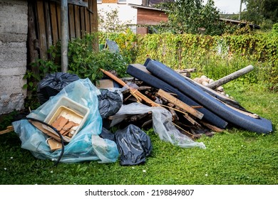 Garbage and a pile of construction debris in the yard of a house.