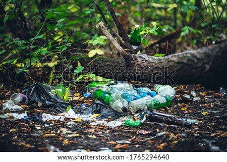Garbage pile in forest among plants. Toxic plastic into nature everywhere. Rubbish heap in park among vegetation. Contaminated soil. Environmental pollution. Ecological issue. Throw trash anywhere.