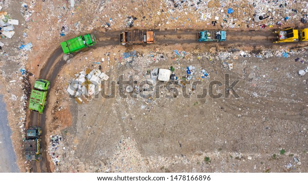 Garbage pile, Trash trucks dump waste\
products polluting in an trash dump or open landfill, Surface and\
subsurface water contamination. Aerial top\
view