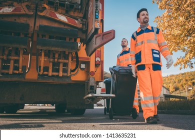 Garbage Removal Men Working For A Public Utility Emptying Trash Container