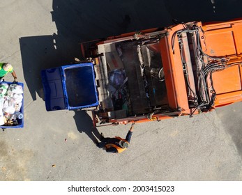 Garbage Removal. The Scavengers Are Rolling The Trash Can To The Garbage Truck, Top View. Garbage Loading Process. Empty And Full Trash Cans.