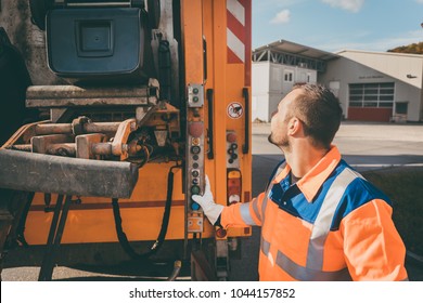 Garbage Removal Worker Emptying Dustbin Into Waste Vehicle
