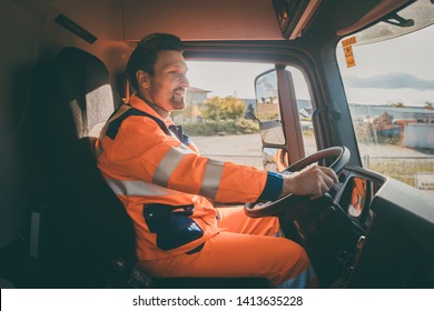 Garbage Removal Worker In Protective Clothing Driving A Dump Truck